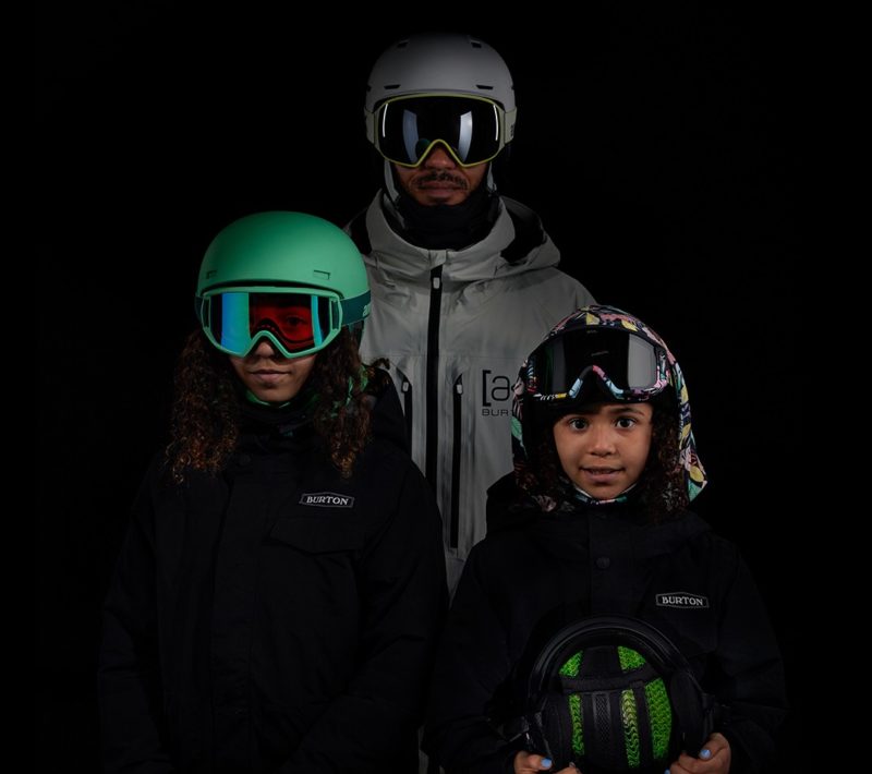 man with two kids dressed in snow gear with helmets