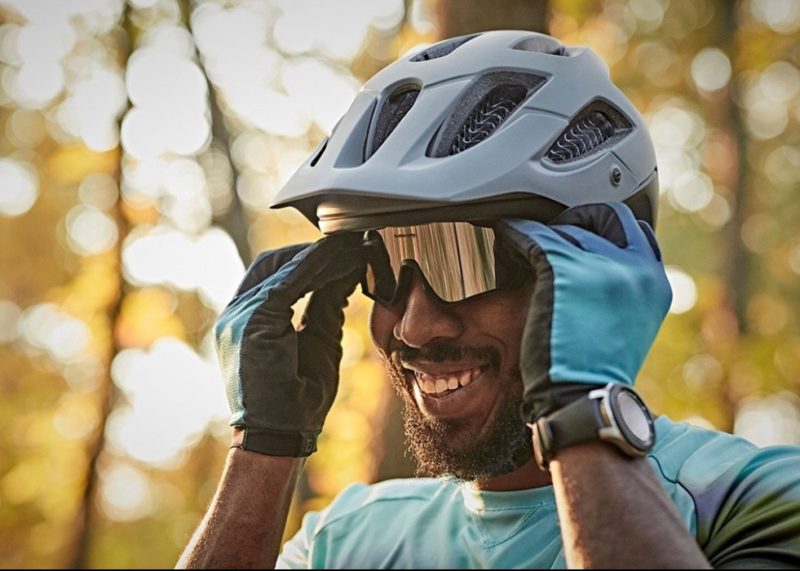 man smiling while wearing helmet and adjusting bike glasses
